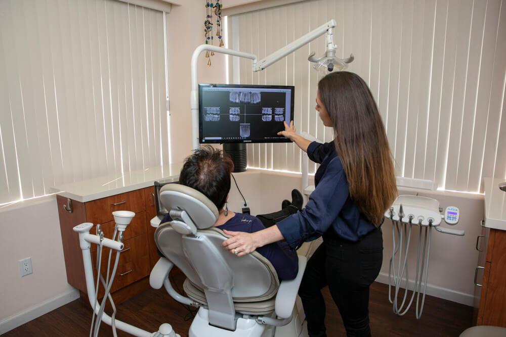 team member of South Bay Dental Smiles talking with patient about xrays in dental chair
